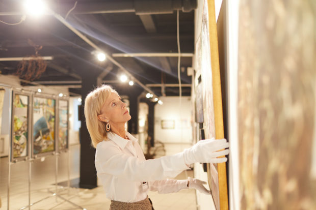 典雅的成熟妇女垂悬的绘画广角画象，当工作在艺术画廊或博物馆时，拷贝空间